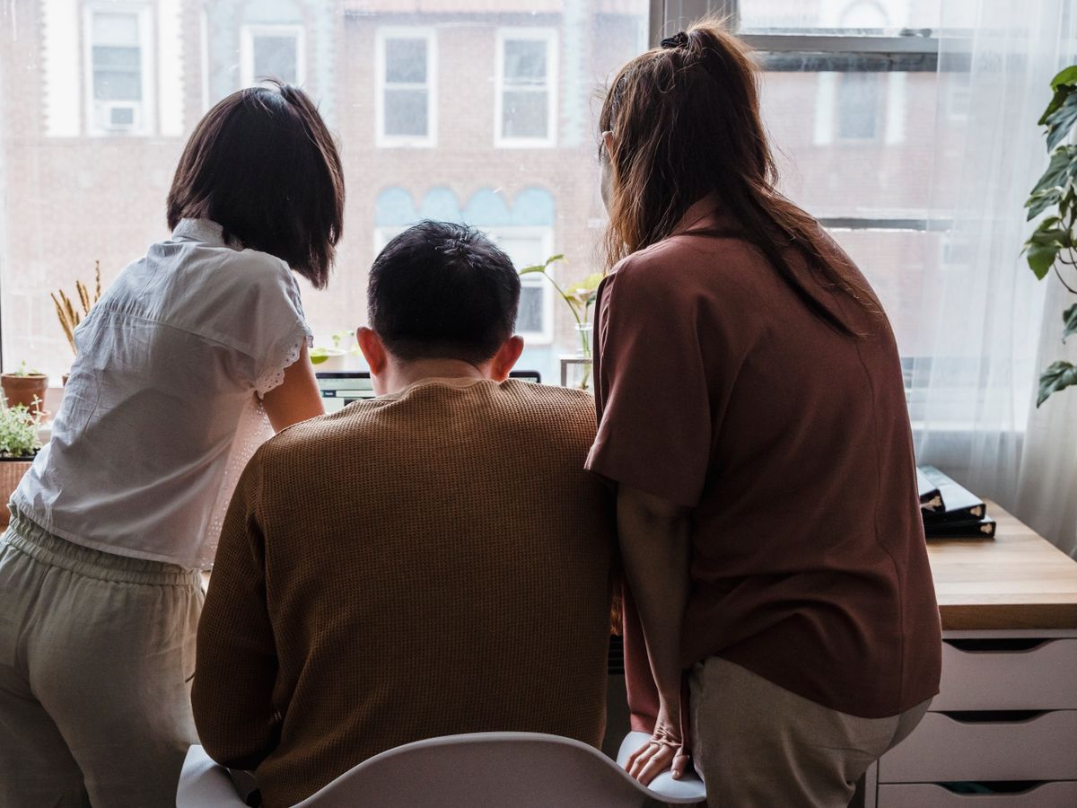 A small team collaborating around a laptop in their office.